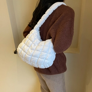 Vue latérale d'un sac bandoulière blanc matelassé porté avec un pull marron chaud