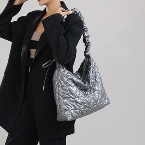 Detail of silver quilted heart handbag with ruched shoulder strap and metallic finish