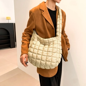 Detail of beige quilted puffer bag featuring a fluffy square texture and wide strap