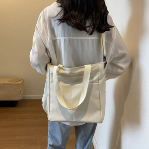Vue arrière d'un grand sac fourre-tout imperméable blanc crème porté par un mannequin en ville