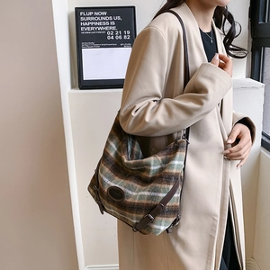 Sac à épaule en laine à carreaux d'hiver avec bandoulière en cuir brun sur manteau beige