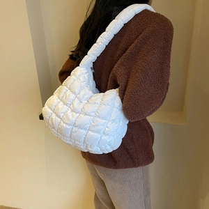 Détail du sac à bandoulière matelassé blanc montrant sa texture douce porté par un modèle