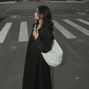 Chic sac bandoulière matelassé blanc porté avec un trench noir en style urbain