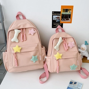 Détail d'un sac à dos en nylon rose avec de mignons charms étoiles en peluche et zip tressé