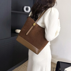 Détail d'un grand sac fourre-tout en daim marron avec des sangles en cuir et boucle dorée