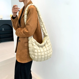 Detailed close-up of cream quilted nylon shoulder bag with soft padding and wide strap