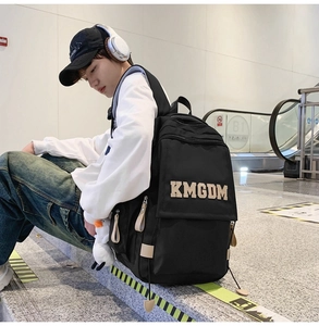 Detail of black nylon backpack with KMGDM embroidery and a white duck plush charm