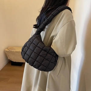 Gros plan d'un sac hobo noir matelassé aspect bouffant porté par un mannequin