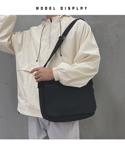 Gros plan d'un sac messager en toile noire avec bandoulière réglable porté par un mannequin