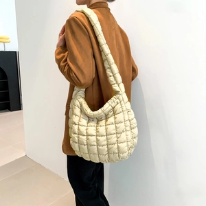 Detail of quilted puffy shoulder bag in creamy white nylon on female model