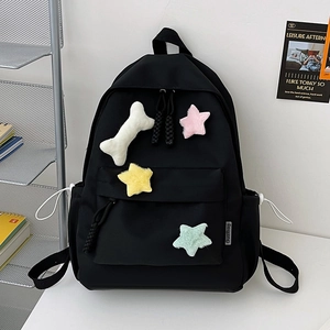 Détail d'un sac à dos noir en nylon avec des écussons en peluche d'os et d'étoiles sur table