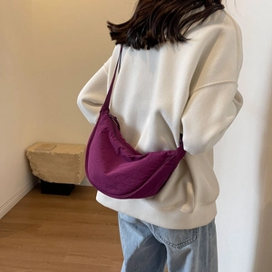 Detail of a deep purple crescent crossbody bag with minimalist pleated fabric texture