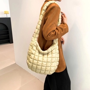Detail view of cream quilted cotton crossbody bag showing texture and drape on model