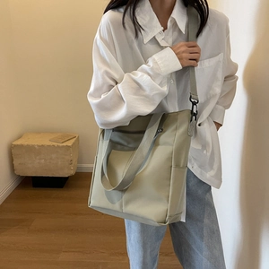 Détail d'un sac cabas en nylon imperméable avec deux poches avant et une large bandoulière