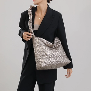 Detail of silver quilted handbag featuring heart patterns and ruched strap on model