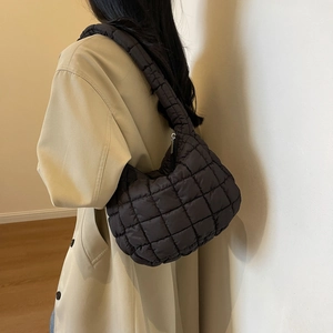 Détail d'un sac bandoulière matelassé noir avec texture bouffante et fermeture éclair métal