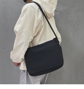 Vue latérale d'un sac messager en toile noire sur modèle montrant la grande capacité