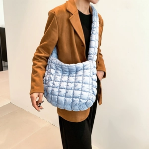 Light blue quilted puffer crossbody bag with soft texture shown on model in side view
