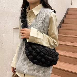 Détail d'un sac bandoulière matelassé noir avec fermeture dorée et tissu en coton gaufré