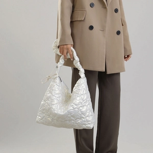 Close-up of heart-quilted white nylon bag with gathered handle and shoulder strap