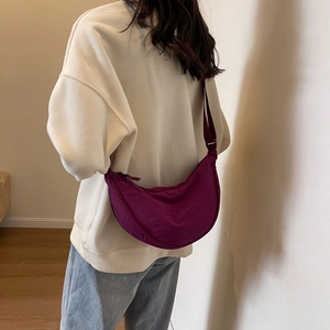 Detail of a dark purple crescent crossbody bag featuring smooth fabric and a wide strap