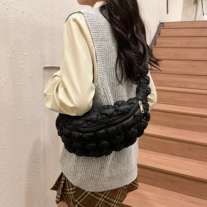 Détail du sac bandoulière matelassé noir sur mannequin dans un intérieur moderne
