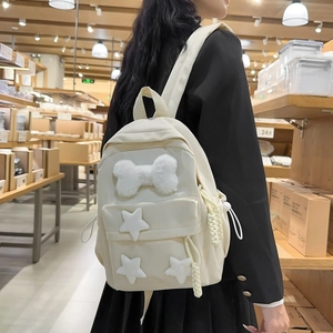 Detailed back view of a minimalist cream nylon backpack with plush star and bone charms