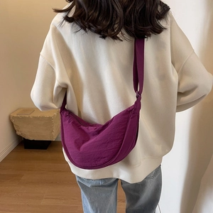 Rear view of a model wearing a purple crescent nylon crossbody bag with adjustable strap