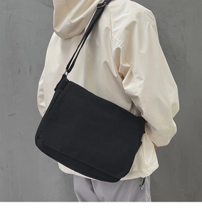 Détail de la besace minimaliste en toile noire avec bandoulière réglable sur modèle