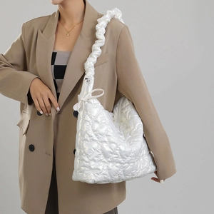 Detailed view of a white heart-quilted shoulder bag with ruched decorative straps