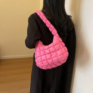Gros plan sur le sac à main matelassé rose vif porté comme un sac à bandoulière élégant