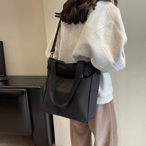 Vue latérale d'un grand sac fourre-tout noir en nylon imperméable porté par un mannequin