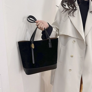 Détail du sac cabas en daim noir avec anneaux dorés et base en cuir lisse de haute qualité