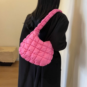 Détail du sac bandoulière matelassé rose vif montrant la texture douce sur le manteau