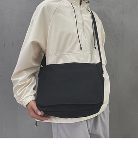 Sac bandoulière minimaliste en toile noire avec large sangle réglable porté par un mannequin