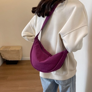 Detailed back view of a purple crescent nylon crossbody bag worn by a model