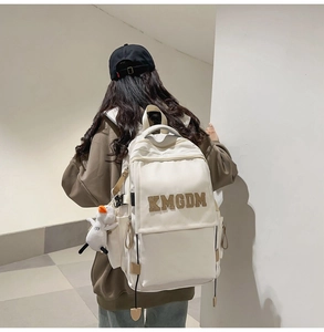 Detail of white nylon backpack with KMGDM logo, large front pocket and plush duck charm