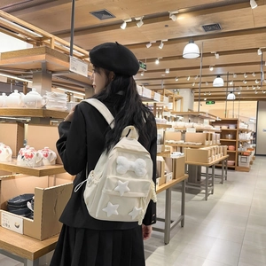 Detail of off-white canvas backpack with plush bone and star patterns on a female model