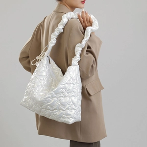 Detail of white quilted nylon handbag with heart pattern shown on a model's shoulder