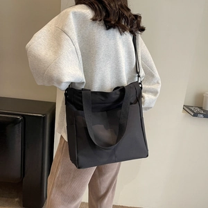 Détail du sac cabas en nylon imperméable avec bandoulière réglable et grande poche frontale
