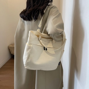 Detail of a minimalist cream canvas tote bag showing its side pockets and functional design