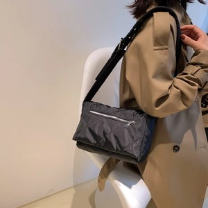 Borsa a tracolla trapuntata nera in nylon indossata con un trench kaki dal design minimal