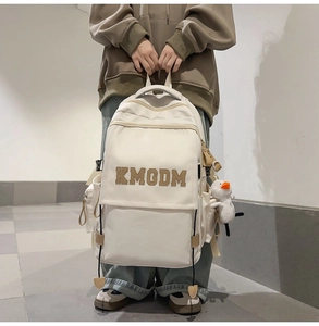 Detail of off-white nylon backpack featuring KMODM letter patch and cute duck plush charm