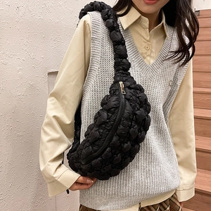Sac bandoulière matelassé noir en forme de lune porté par un mannequin en extérieur