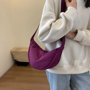 Detailed view of purple crescent nylon crossbody bag with minimalist pleated texture