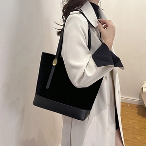 Sac fourre-tout minimaliste en daim noir avec bandoulière en cuir porté par un modèle