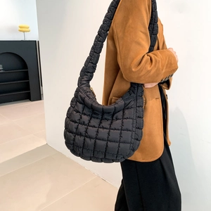 Detail of black quilted puffer shoulder bag showing soft padded texture and crescent shape