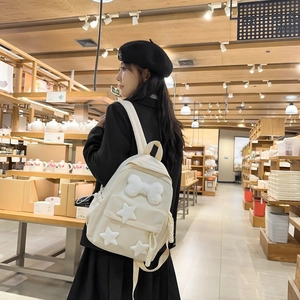 Detail of a creamy nylon backpack with white plush bows and star patches on a woman