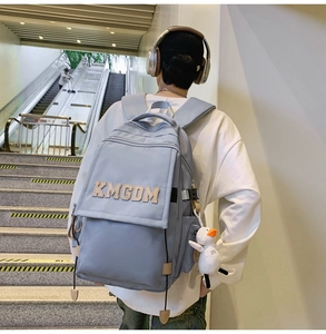 Detail of light blue nylon backpack with embroidered logo and white bird plush charm