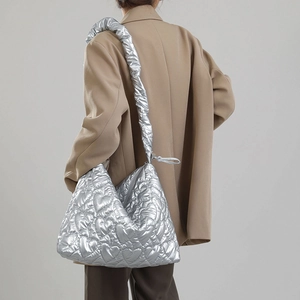 Silver quilted tote bag with heart patterns and scrunchie strap shown on model shoulder